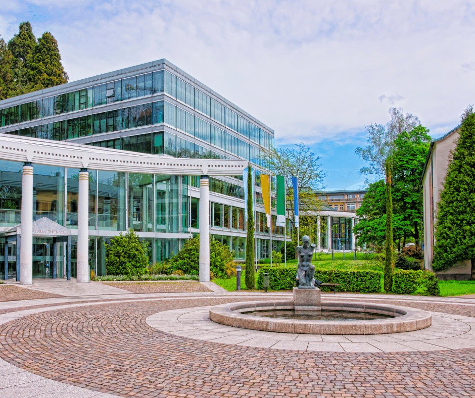 Indoor thermal pool at Caracalla Spa in Baden-Baden, Germany, featuring modern glass architecture, turquoise waters, and relaxing wellness spaces surrounded by greenery.