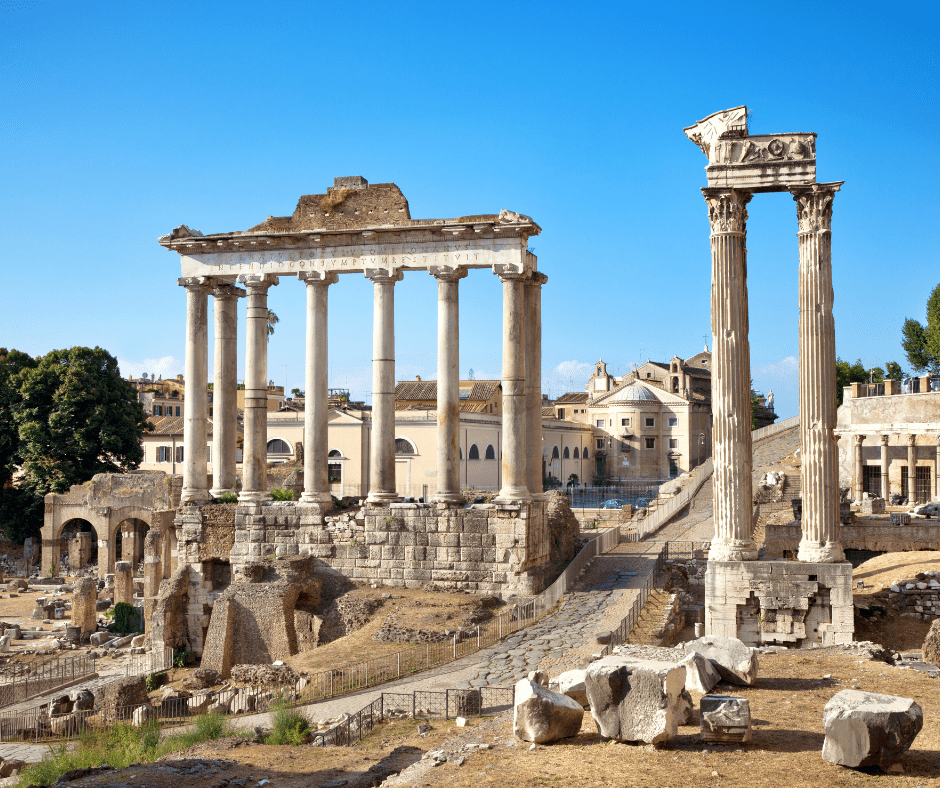 View of the Roman Forum ruins with ancient columns, arches, and temples under a clear sky in Rome, Italy.