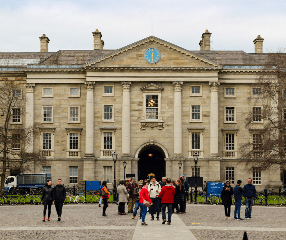 "Students gathering outside the main entrance of Trinity College Dublin on a sunny day