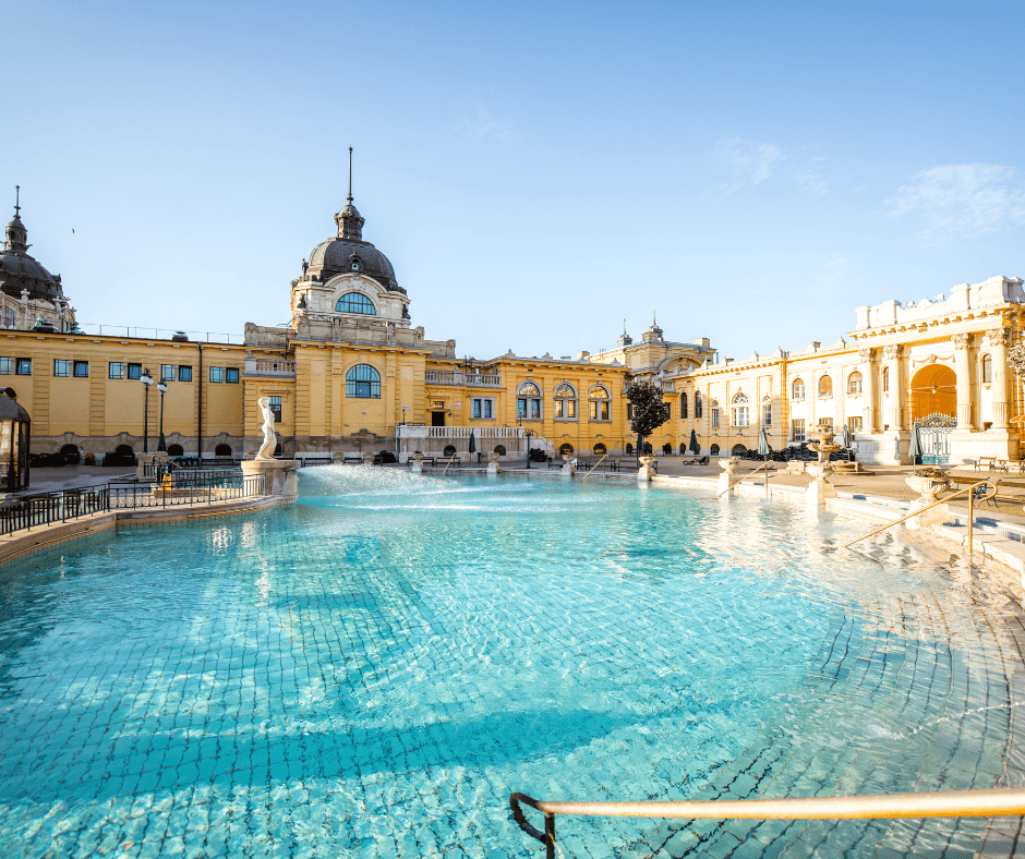 Széchenyi Thermal Bath in Budapest, Hungary, featuring neo-Baroque architecture and steaming outdoor pools surrounded by historic colonnades.