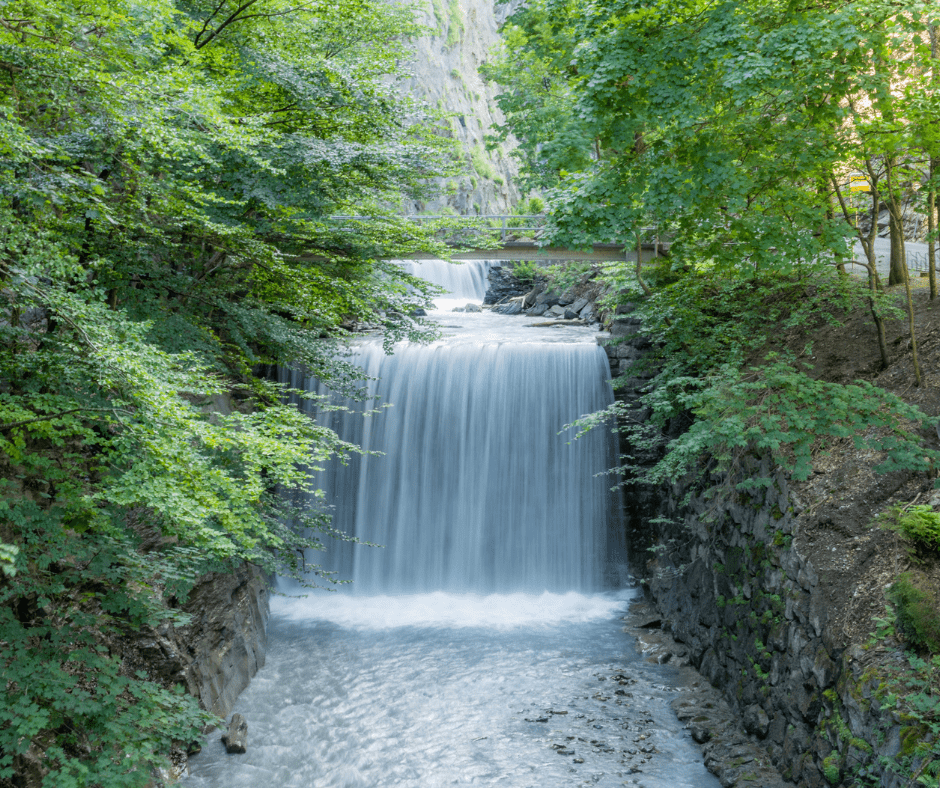 Narrow Tamina Gorge in Bad Ragaz, Switzerland, with steep rock walls, mist rising from the thermal spring, and a walking path leading into the canyon.