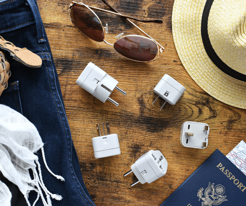 A flat lay of travel essentials, including a power converter, voltage travel adapter (220V to 110V), and packing converters and adapters for trips to Europe, the UK, Australia, or North America. These items are designed to ensure compatibility with various plug types and voltage systems during international travel.