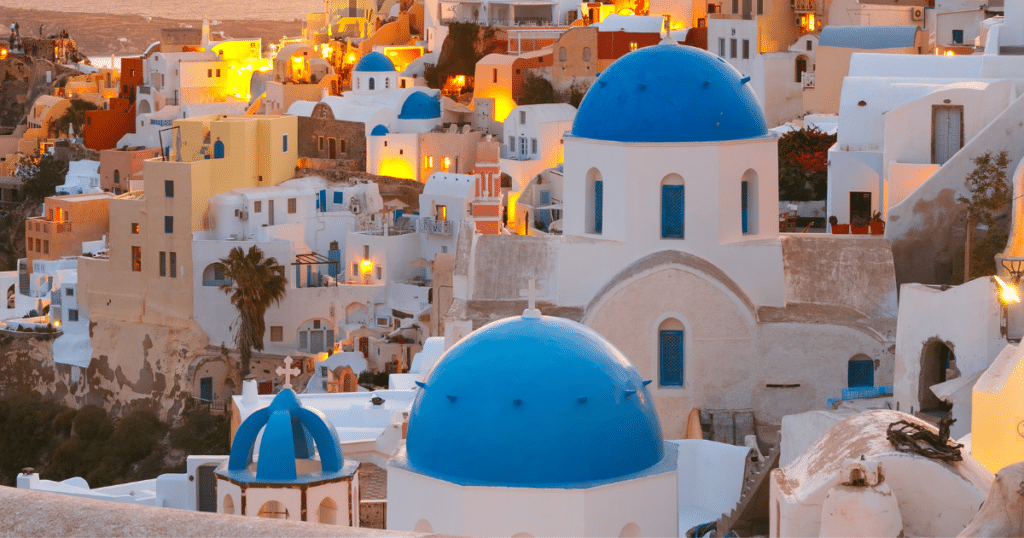 Santorini sunset view over Oia with white buildings and blue domes, best time to visit Greece