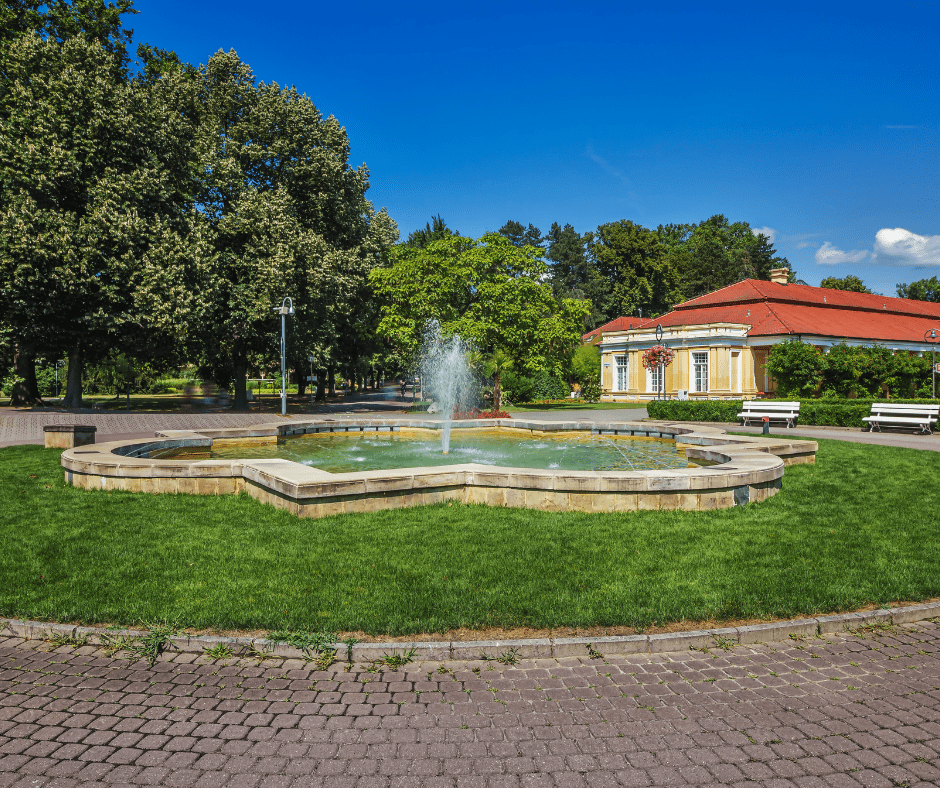 Peaceful park on Spa Island in Piešťany, Slovakia, featuring manicured lawns, walking paths, and thermal spa buildings surrounded by greenery.