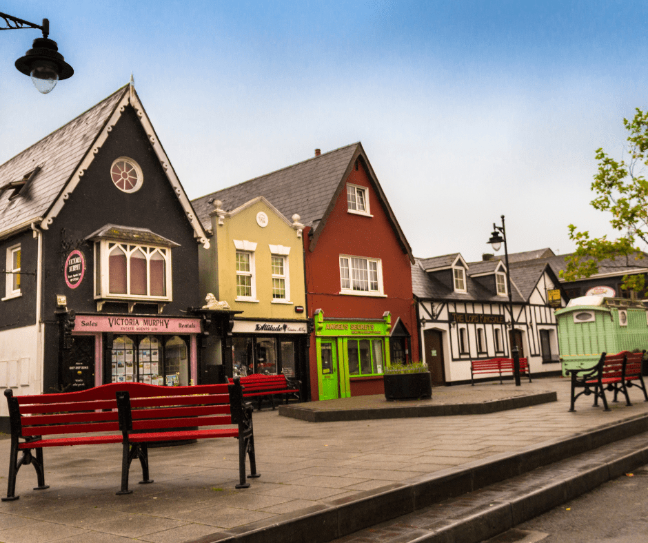 Colorful buildings surrounding a quiet square in Kinsale, Ireland, with cobblestone streets, outdoor seating, and a relaxed small-town atmosphere ideal for budget-friendly travel.