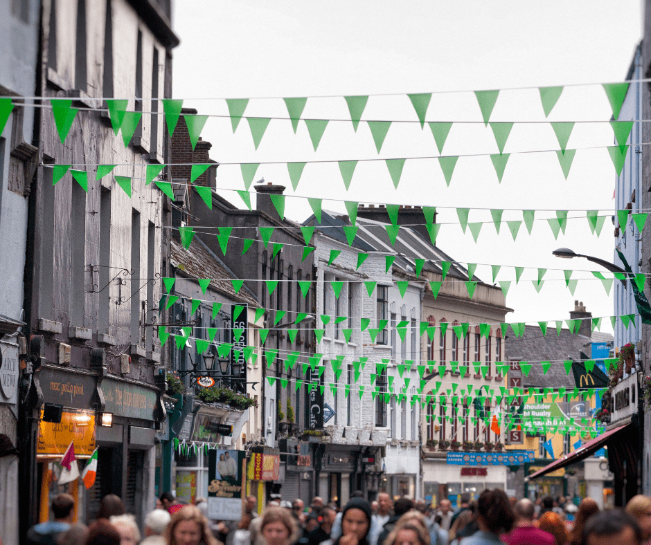 Crowds celebrating St. Patrick’s Day on Dublin’s main shopping street, with Irish flags, green decorations, and festive street performers lining the lively city center.