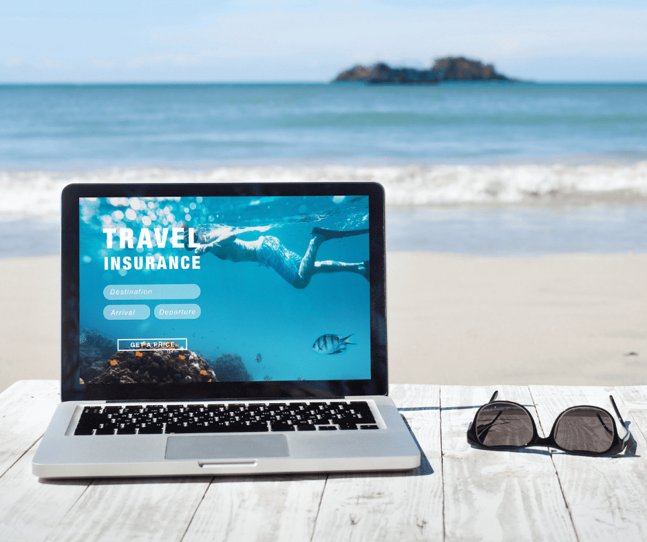 A laptop on the beach displaying a travel insurance website, symbolizing the convenience of securing premium travel insurance for European adventures from anywhere.