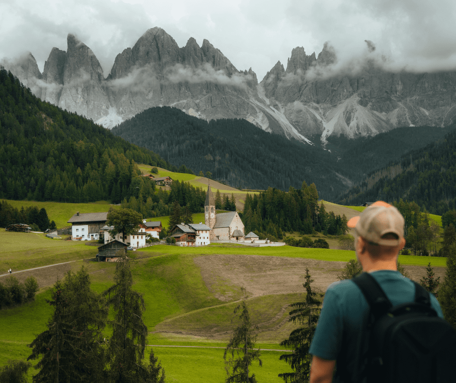 Solo traveler overlooking a mountain village in the Dolomites, representing independent travel in Europe.